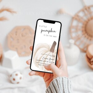 May include: A phone screen displaying a baby shower invitation with a watercolor illustration of a white pumpkin. The invitation reads "A little pumpkin is on the way" and includes the name "Emma Brown" and the date "October 20th at 2:00 PM".
