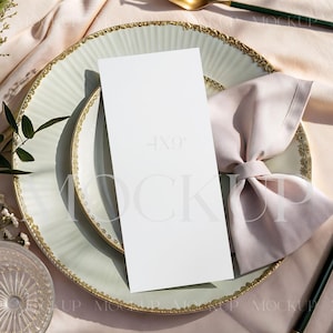 May include: A mock-up of a place setting with a white menu card, a pale green plate with a gold rim, a pink napkin, and gold cutlery with dark green handles. The text "4x9" is visible on the menu card.