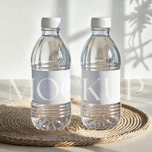 Puede incluir: Dos botellas de agua de plástico transparente con etiquetas blancas sobre un mantel individual de mimbre marrón. Las botellas están sobre una superficie blanca con una sombra de una ventana.
