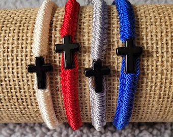 May include: Four braided bracelets with black cross charms. The bracelets are in white, red, gray, and blue.