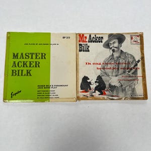 Peut inclure: Deux pochettes de disques vinyles vintage. L'une est verte et blanche avec le texte "Master Acker Bilk" et "Esquire". L'autre pochette présente un homme portant un chapeau et le texte "Mr. Acker Bilk".