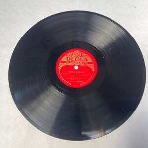 Può includere: Un disco in vinile nero con un'etichetta rossa e dorata. L'etichetta recita "DECCA THE SUPREME RECORD" e include testo in lingua straniera. L'articolo è un oggetto musicale vintage.