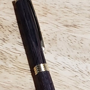金色の金具が付いた手作りの木製ペン。黒インク