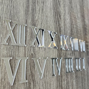 May include: Silver Roman numeral clock numbers for a DIY clock project. The numbers include I, II, III, IV, V, VI, VII, VIII, IX, X, XI, XII.