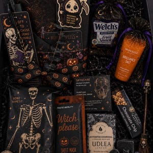 May include: A gift box containing a skeleton-themed bookmark, a grim reaper charm, Welch's fruit snacks, Spongelle hand cream, a charcoal mask, a Witch Please pumpkin spice sheet mask, an Udlea charcoal bath bar, a chocolate chip granola bar, and a skull.