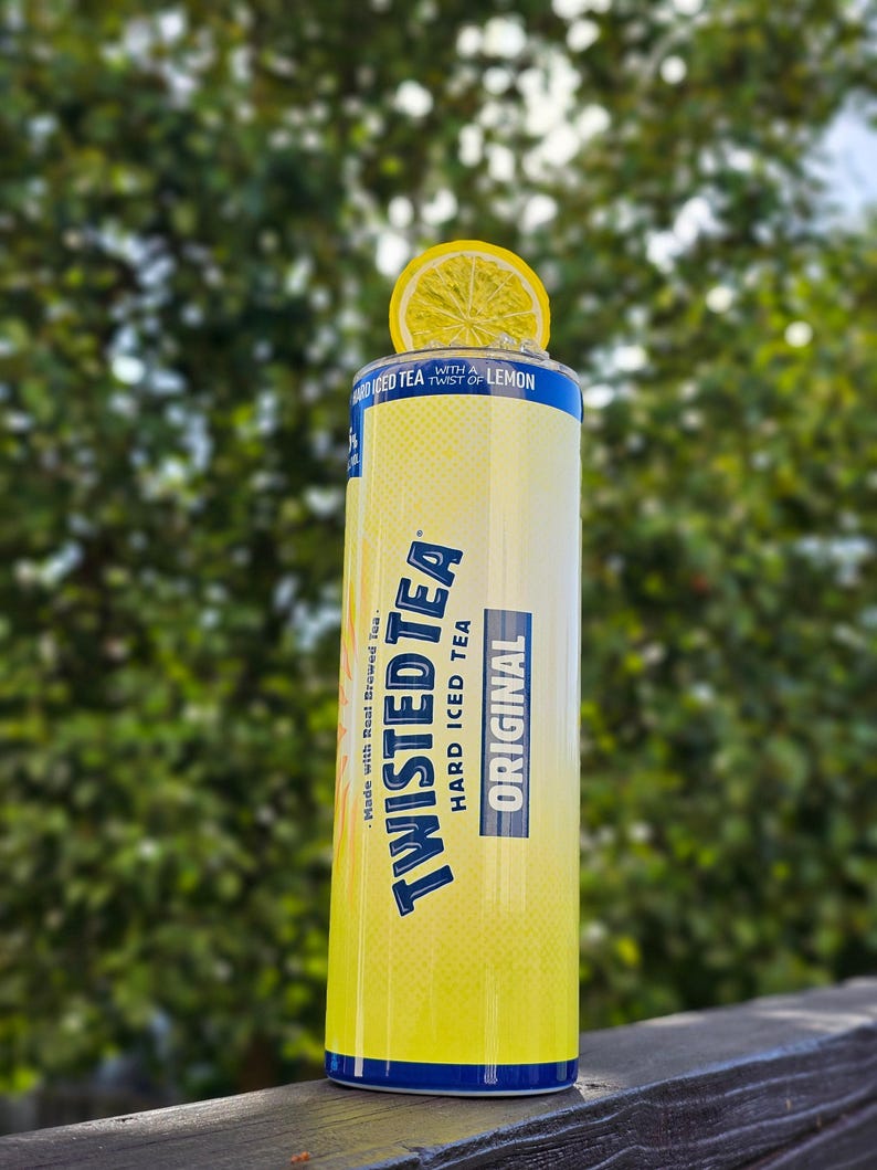 May include: A yellow can of Twisted Tea Hard Iced Tea with a lemon wedge on top. The can has blue text that reads "Made with Real Brewed Tea", "Twisted Tea", "Hard Iced Tea", and "Original". The can also has a blue stripe with the text "With a Twist of Lemon".