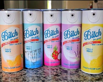 May include: Five spray bottles with the text "Bitch be gone" in a script font. Each bottle has a different color scheme and a graphic of fruit or laundry. The bottles also say "Kills 99.9% of Thots & Bitches" and "Eliminates Hoes."