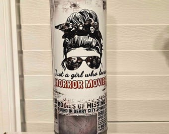 May include: A stainless steel tumbler with a horror movie theme. The design features a woman with sunglasses and the text "Just a girl who loves HORROR MOVIES." The tumbler also has newspaper-style graphics and a speaker base.