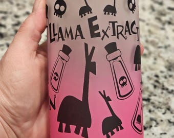May include: A glass beverage can with a bamboo lid. The can features a gradient from pink to white, with black llama and skull graphics. The text "Llama Extract" is printed on the front.
