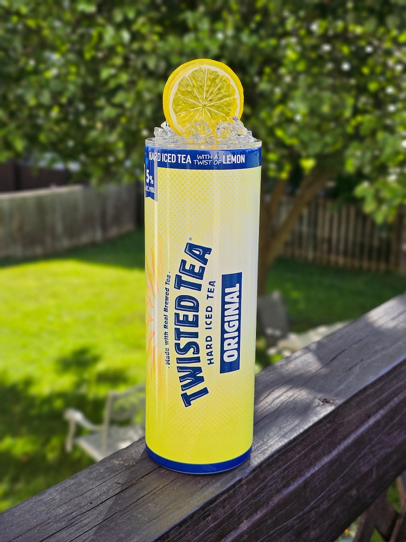 May include: A yellow can of Twisted Tea Hard Iced Tea with a lemon wedge on top. The can has blue text that reads "Made with Real Brewed Tea" and "Twisted Tea Hard Iced Tea Original".