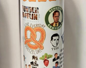 May include: White tumbler featuring various images and text from the TV show "The Office." The design includes the show's logo, character portraits, and phrases like "Schrute Certified" and "Pretzel Day." The tumbler is cylindrical and has a white base.