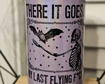 May include: A purple iridescent can with a black graphic of a skeleton holding a bat with the text "THERE IT GOES MY LAST FLYING F*CK".