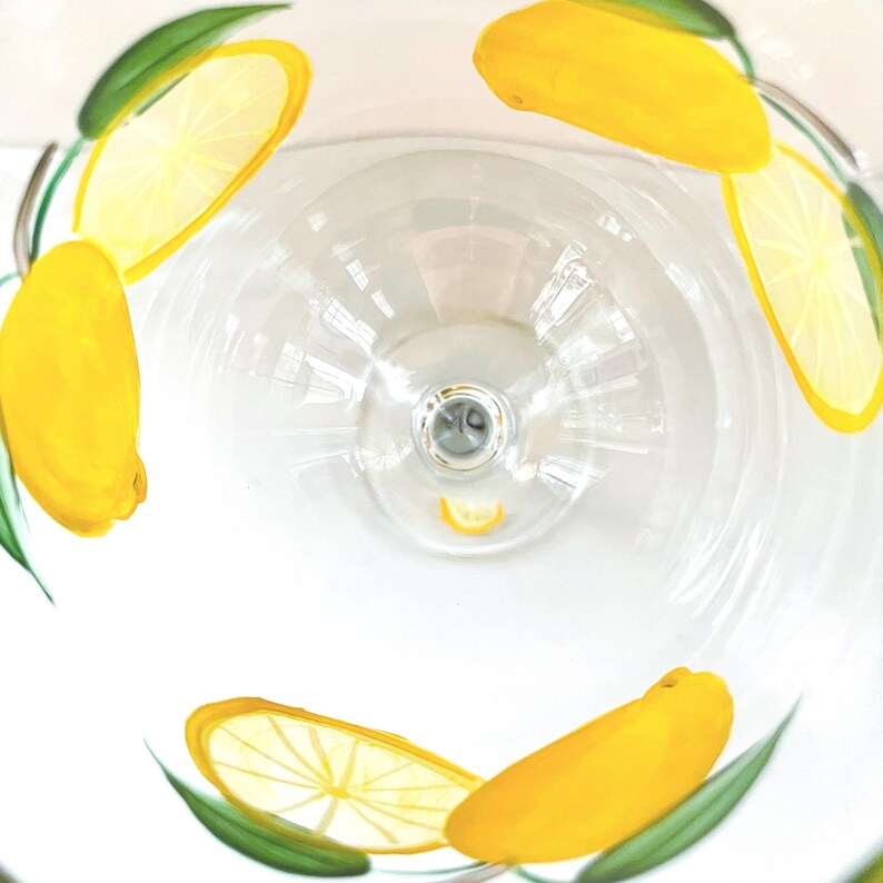 May include: Clear glass serving bowl with hand-painted yellow lemons and green leaves around the rim. The bowl has a wide, shallow design, perfect for serving salads or fruit. The lemons are bright yellow with white segments.