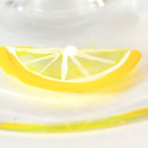 May include: A close-up of a painted lemon slice with a white interior and a bright yellow rind. The lemon slice is set against a soft, white background, creating a fresh and vibrant aesthetic. The image evokes a sense of refreshment and citrus.
