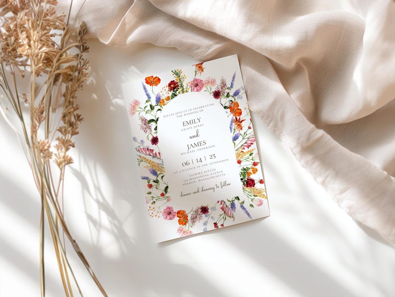 May include: A wedding invitation with a floral wreath design in shades of pink, red, orange, yellow, and blue. The text reads "Emily and James" with the date "06 | 14 | 25".