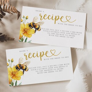 K&ouml;nnte beinhalten: Zwei wei&szlig;e Karten mit goldener Schrift, auf denen "Teile ein Rezept mit der Braut zu sein" steht. Die Karten zeigen eine Biene und gelbe Blumen.