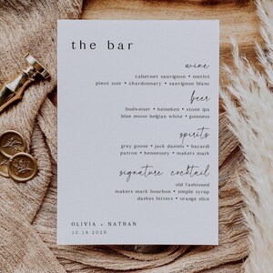 May include: A white rectangular bar menu with the text "the bar" at the top. The menu lists wine, beer, spirits, and signature cocktails. The names Olivia and Nathan are at the bottom, with the date 10.18.2025.