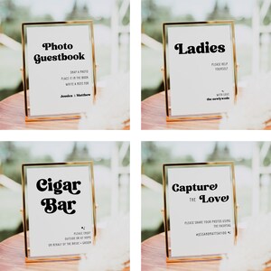 May include: Four gold-framed signs with white backgrounds and black text. The signs read "Photo Guestbook", "Ladies", "Cigar Bar", and "Capture the Love".