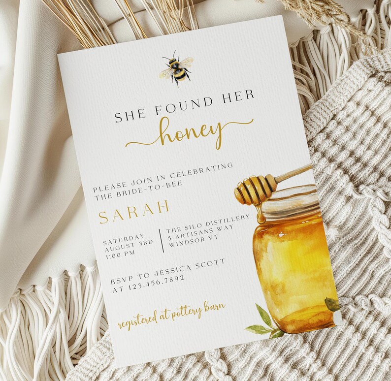 K&ouml;nnte beinhalten: Eine wei&szlig;e Brautduscheinladung mit goldener Schrift, die "She Found Her Honey" lautet. Die Einladung zeigt eine Aquarell-Illustration eines Honigglases mit einem Honigl&ouml;ffel und einer Biene.