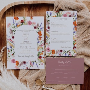 May include: A floral wedding invitation suite with a watercolor design featuring a wreath of flowers in shades of pink, purple, orange, and yellow. The invitation includes the names Emily and James, the date June 14, 2025, and the location Sapphire Estate in Mashpee, Massachusetts. The details card includes information about the reception, accommodations, and transportation. The RSVP card is a light purple color with a floral design and the text "Kindly RSVP by August 1st, 2024".