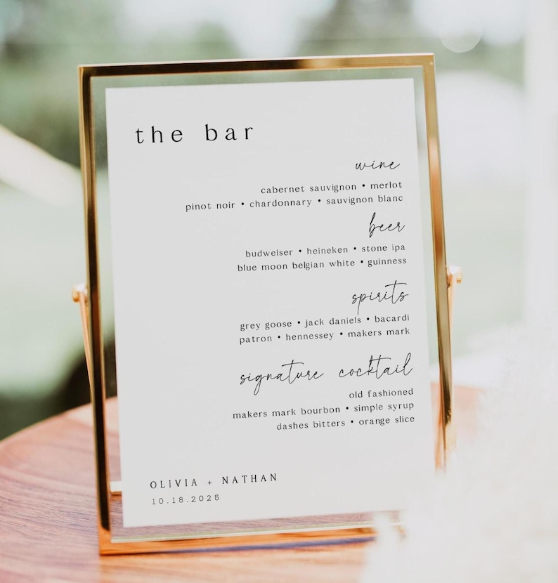 May include: A gold-framed sign with the words "the bar" at the top. The sign lists wine, beer, spirits, and signature cocktail options. The names Olivia and Nathan, along with the date 10.18.2026, are at the bottom.