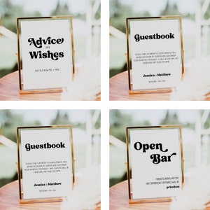 May include: Four gold-framed signs with white backgrounds and black text. The signs read "Advice and Wishes for the new Mr. & Mrs.", "Guestbook", "Guestbook", and "Open Bar".
