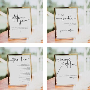 Pu&ograve; includere: Quattro cartelli con cornice dorata, sfondo bianco e testo nero. I cartelli sono per un ricevimento di nozze e includono il testo "date jar", "let love sparkle", "the bar" e "s'mores station".