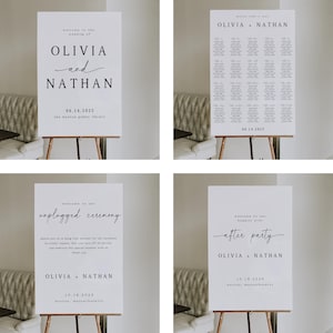 May include: Four white wedding signs on wooden easels. The signs feature black text, including names, dates, and locations. One sign reads "Olivia and Nathan" with the date and location. Another sign says "unplugged ceremony".