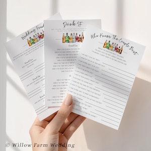 May include: Three white paper game cards for a wedding, held by a hand. The cards have text and illustrations of bottles. The top card reads "Drink If", the middle card reads "Who Knows The Couple Best", and the left card reads "Wedding Feud".