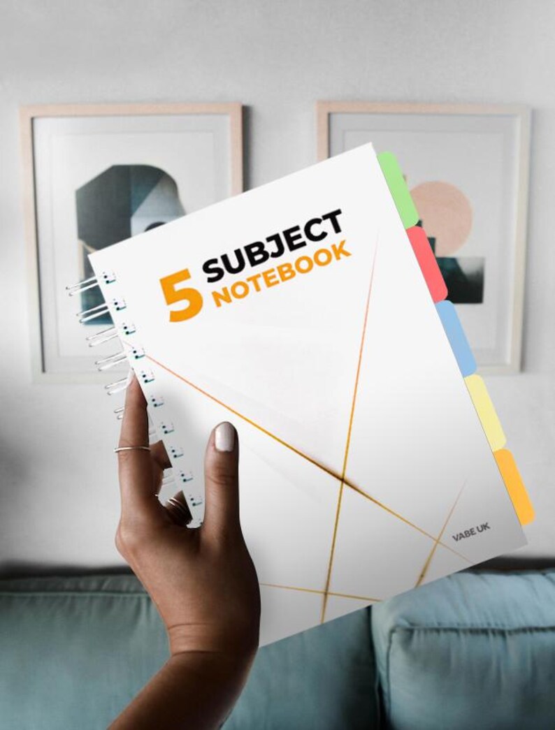 May include: A white notebook with a gold geometric design and the text "5 Subject Notebook". The notebook has five coloured tabs on the side.