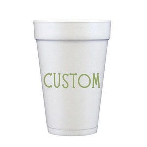 May include: A white foam cup with the word "CUSTOM" printed in green. The cup has a slightly textured surface and a tapered design, wider at the top and narrower at the base. The cup is empty.