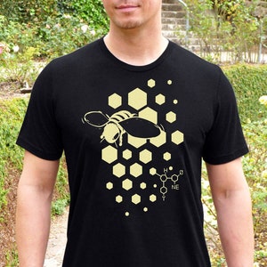 May include: A black t-shirt with a yellow graphic of a bee flying over a honeycomb pattern. The graphic also includes a chemical formula for honey.