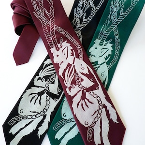 May include: Four neckties in shades of burgundy, black, and green, each featuring a silver mythical creature design. The ties are arranged diagonally, showcasing the detailed artwork and varying colors. The ties are made of a smooth fabric.
