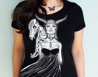 May include: Black t-shirt with a white graphic print of a woman with horns and a creature on her shoulder. The woman is wearing a dress and a necklace with a butterfly pendant.
