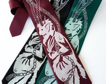 May include: Four neckties in shades of burgundy, black, and green, each featuring a silver mythical creature design. The ties are arranged diagonally, showcasing the detailed artwork and varying colors. The ties are made of a smooth fabric.