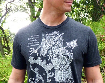 May include: A dark gray t-shirt with a white graphic print of a dragon and a goblin playing a guitar. The text "Chaotic Awesome Cellars Goblin Bard Brandy" is printed below the graphic.