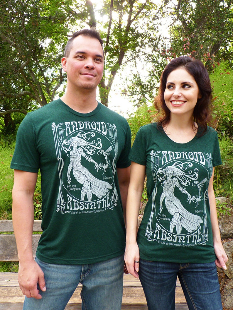 May include: Two people wearing matching dark green t-shirts with a white graphic design. The design includes the word "ANDROID", a woman, and the word "ABSINTH". The shirts are paired with blue jeans.