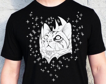 May include: Black t-shirt with a white graphic of a cat's head wearing a crown and surrounded by stars.