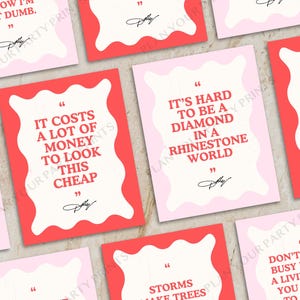 May include: A collection of pink and red quote cards with white text. The cards feature various quotes, including "It costs a lot of money to look this cheap." The cards are arranged on a light-colored surface.
