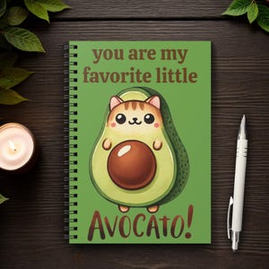 May include: A green spiral notebook with a cute cartoon avocado with a cat face inside. The text on the cover reads "You are my favorite little avoca-to!"