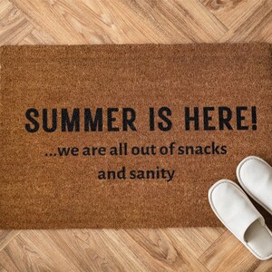 May include: A brown coir doormat with the text "SUMMER IS HERE! ...we are all out of snacks and sanity" in black lettering.