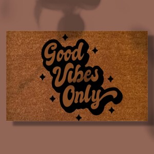 May include: A brown doormat with the text "Good Vibes Only" in black and brown lettering. The text is in a retro font style.