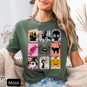 Puede incluir: Camiseta verde musgo con una cuadr&iacute;cula de gr&aacute;ficos tem&aacute;ticos de Halloween. Los gr&aacute;ficos incluyen una casa embrujada, una bruja en una escoba, una calavera, caramelos, una ara&ntilde;a, un gato negro, una calavera con un sombrero de bruja, un &aacute;rbol espeluznante y una calabaza. La palabra "Moss" est&aacute; impresa en la parte inferior.