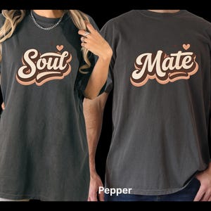 May include: Two matching pepper-colored t-shirts. One shirt says "Soul" with a heart, the other says "Mate" with a heart. The text is in a retro font with cream and brown accents. The word "Pepper" is at the bottom.