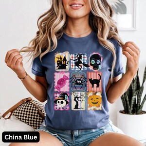 Puede incluir: Camiseta azul China con un dise&ntilde;o de patchwork con ilustraciones de Halloween. El dise&ntilde;o incluye una casa embrujada, una bruja, una calavera, caramelos, una ara&ntilde;a, un gato negro y una calabaza. La camiseta tiene mangas cortas y cuello redondo.