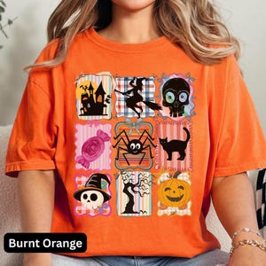Puede incluir: Camiseta naranja quemado con un dise&ntilde;o de patchwork de Halloween. El dise&ntilde;o incluye una casa embrujada, una bruja en una escoba, una calavera, caramelos, una ara&ntilde;a, un gato negro, una calavera con sombrero de bruja, un &aacute;rbol desnudo y una calabaza. El texto "Burnt Orange" est&aacute; en la parte inferior.