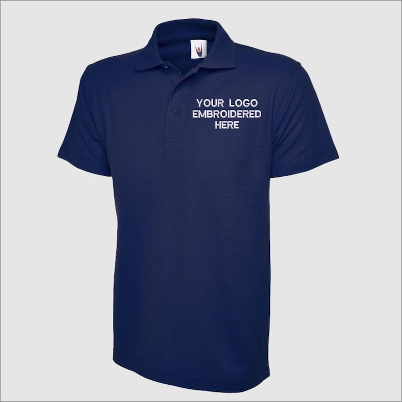 May include: A navy blue polo shirt with short sleeves and a white embroidered logo that says "YOUR LOGO EMBROIDERED HERE".