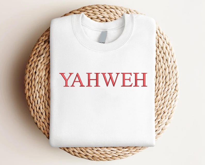 May include: A white crewneck sweatshirt featuring the word YAHWEH embroidered in red capital letters across the center of the chest. The garment has a ribbed collar and long sleeves, presented in a clean, folded layout for clear visibility.