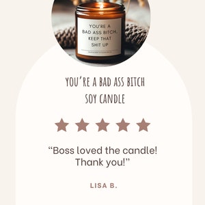 May include: A brown soy candle in a glass jar with a white label. The label reads "YOU'RE A BAD ASS BITCH, KEEP THAT SHIT UP." The image also includes customer reviews and the text "YOU'RE A BAD ASS BITCH SOY CANDLE."