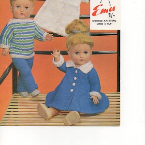 May include: Two dolls wearing knitted outfits. The doll on the left is wearing a blue and green striped sweater and blue pants. The doll on the right is wearing a blue dress with a white collar and white buttons. The dolls are sitting on a wooden surface. The image includes the text "Emu Double Knitting and 4 Ply 1/- 6115".